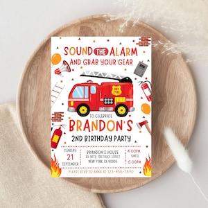 Puede incluir: Una invitación de cumpleaños con un gráfico de camión de bomberos rojo. La invitación incluye el texto "Sound the Alarm and Grab Your Gear" y los detalles de la fiesta de cumpleaños número 2 de Brandon, incluyendo la fecha, hora y lugar.
