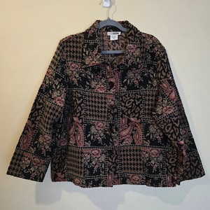 May include: A long-sleeved button-down jacket featuring a patchwork design of black, brown, and muted pink patterns including floral motifs, houndstooth, and animal print. The garment has a standard collar and a front button closure system.
