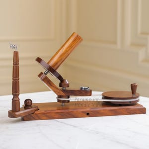 Peut inclure: Un ensemble en bois comprenant un dévidoir à fil et un bobinoir. L'ensemble est en bois brun foncé et comprend un dévidoir à fil avec un poteau vertical et un bobinoir avec une base circulaire. Le texte "Paramount Handic India" est visible.