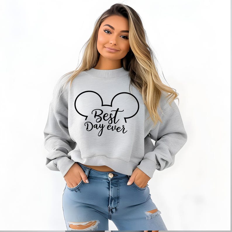 May include: A light gray sweatshirt with a black Mickey Mouse ear design and the text "Best Day ever". The sweatshirt is a crew neck style.