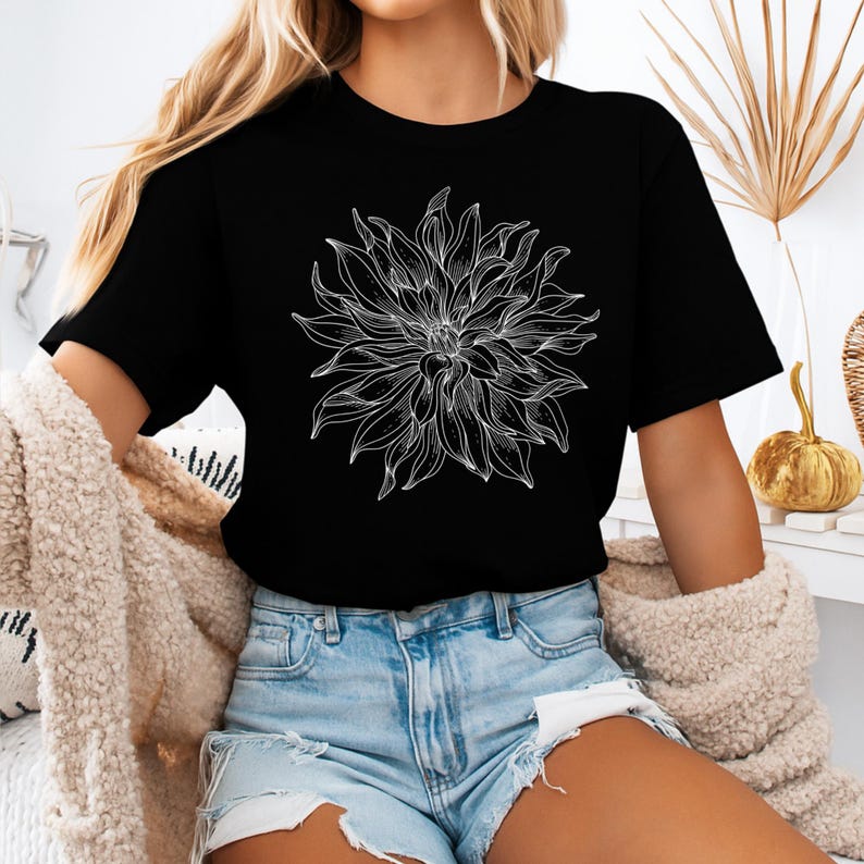 May include: Black t-shirt with a large white floral design. The detailed flower graphic is the focal point, with intricate lines defining the petals. The shirt is worn with denim shorts. The overall style is casual.