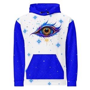 May include: A long-sleeve hoodie featuring a white front panel with a central graphic of a stylized eye with blue and purple lashes, surrounded by blue four-pointed stars. The sleeves, hood, and front pocket are a solid deep blue with white speckles.