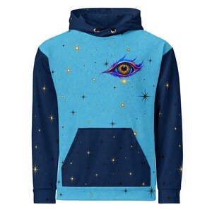 May include: A long-sleeve hooded sweatshirt featuring a light blue center panel with a detailed eye graphic and a star-filled sky pattern. The sleeves, hood, and front kangaroo pocket are dark navy blue, also decorated with small black and gold stars.
