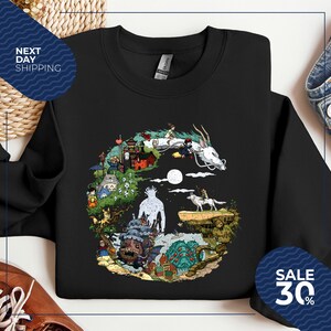 a black t-shirt with a colorful graphic design depicting various characters and elements from the animated film "Spirited Away".