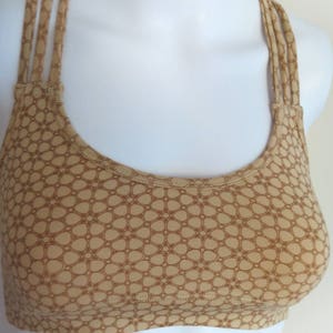 May include: A brown sports bra with a geometric pattern and adjustable straps.