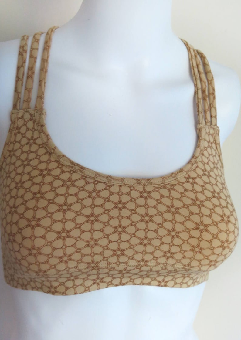 May include: A brown sports bra with a geometric pattern and adjustable straps.