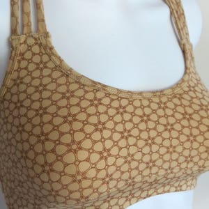 May include: A brown and tan sports bra with a geometric pattern. The bra has a scoop neck and adjustable straps.