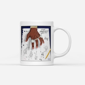 Puede incluir: Taza de cerámica blanca con una ilustración de una mano con anillos y una pulsera, sosteniendo cuerdas unidas a figuras de palo. El texto "THE BIGGER ARTIST" se muestra en la taza.