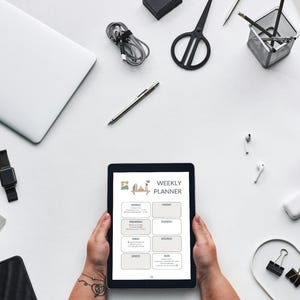Könnte beinhalten: Draufsicht auf einen Arbeitsplatz mit einem Tablet, das einen Wochenplaner anzeigt. Weitere Artikel sind ein Laptop, eine Uhr, Stifte, eine Schere, Kaffee und ein Smartphone, alles auf einer weißen Oberfläche angeordnet.
