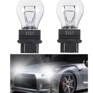 Puede incluir: Dos bombillas automotrices transparentes con el n&uacute;mero "3157" impreso en la base negra. La imagen tambi&eacute;n muestra un coche deportivo plateado con los faros encendidos, lo que sugiere el uso de las bombillas en veh&iacute;culos.