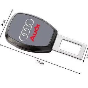 K&ouml;nnte beinhalten: Schwarze und graue Autosicherheitsgurtschnalle mit Audi-Logo. Die Schnalle ist 10 cm lang, 4 cm breit und der Metallteil ist 2,2 cm breit. Das Audi-Logo ist rot und silber.