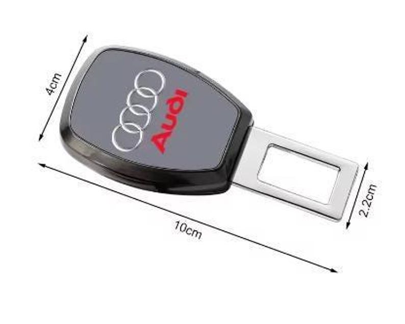 K&ouml;nnte beinhalten: Schwarze und graue Autosicherheitsgurtschnalle mit Audi-Logo. Die Schnalle ist 10 cm lang, 4 cm breit und der Metallteil ist 2,2 cm breit. Das Audi-Logo ist rot und silber.