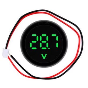 Puede incluir: Un voltímetro digital redondo y negro que muestra "28.7" en verde. Tiene cables rojos y negros conectados, con un conector blanco. El voltímetro está diseñado para medir el voltaje eléctrico, con una flecha hacia abajo.