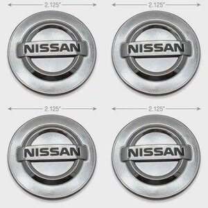 Peut inclure: Quatre enjoliveurs Nissan argentés, chacun mesurant 5,4 cm de diamètre. Les enjoliveurs ont un design circulaire avec le logo Nissan au centre. Le logo est de forme rectangulaire avec le nom de la marque en majuscules.