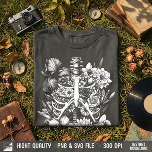 T-shirt flat lay on grass with dried flowers and vintage camera, showing the retro anatomy art graphic.