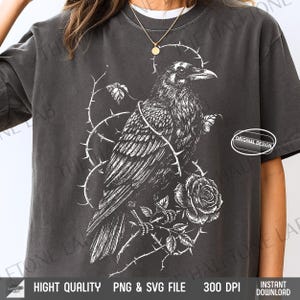 Puede incluir: Camiseta gris oscuro con una ilustración blanca de un cuervo sobre una rama espinosa y una rosa. El diseño incluye el texto "ORIGINAL DESIGN" y "HIGHT QUALITY PNG & SVG FILE 300 DPI INSTANT DOWNLOAD".