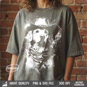 May include: Gray t-shirt featuring a white graphic of a Golden Retriever wearing a cowboy hat and bandana. The shirt has the text "HIGH QUALITY PNG & SVG FILE 300 DPI INSTANT DOWNLOAD" at the bottom.