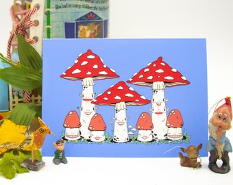 Puede incluir: Un fondo azul con una tarjeta que presenta una ilustración de dibujos animados de setas rojas y blancas con caras sonrientes. Las setas tienen tallos blancos y manchas blancas en los sombreros. Hay pequeñas plantas verdes en la parte inferior de la tarjeta.