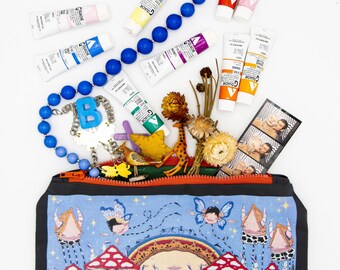 Puede incluir: Una bolsa con cremallera azul y blanca con una ilustración caprichosa de setas y hadas. La bolsa está llena de varios artículos, incluyendo un collar de cuentas azules, tubos de pintura, una figura de jirafa y una tira de cabina de fotos.