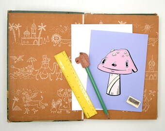 Puede incluir: Un dibujo de un hongo rosa con una cara sonriente sobre un fondo morado. El dibujo está en una hoja de papel con una regla y un lápiz al lado.