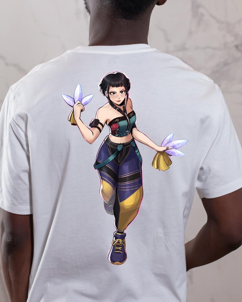 May include: White t-shirt featuring a colorful anime-style illustration of a female character. The character is depicted in a dynamic pose, holding glowing objects. The design incorporates shades of blue, yellow, and purple, creating a vibrant aesthetic.