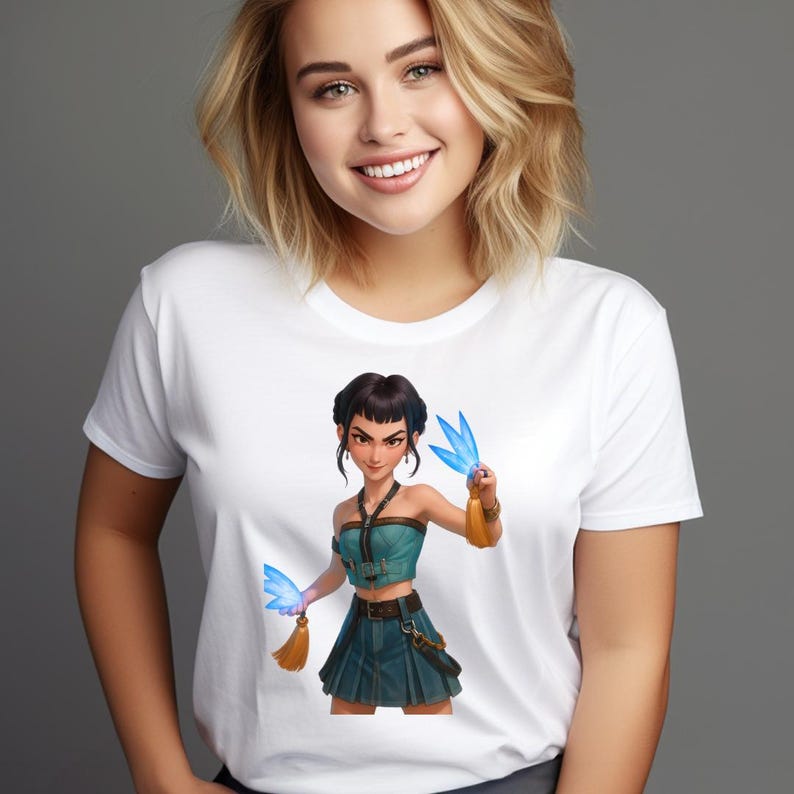May include: White t-shirt featuring a digital illustration of a woman in a teal crop top and skirt, holding blue, wing-shaped objects. The illustration has a fantasy theme with gold accents and a determined expression.