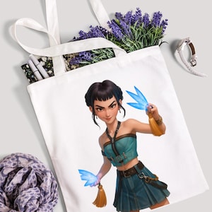 May include: White tote bag featuring a digital illustration of a woman with blue energy effects. The woman is wearing a teal top and skirt. The bag is filled with lavender and other items.