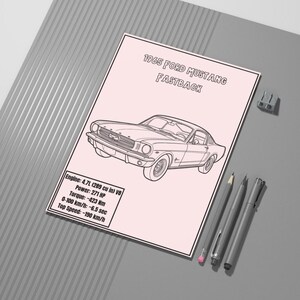 Puede incluir: Ilustración rosa y blanca de un Ford Mustang Fastback de 1965. La imagen incluye especificaciones del motor: 4.7L V8, 271 CV, par motor de 423 Nm, 0-100 km/h en 6,5 segundos y una velocidad máxima de 190 km/h. También hay bolígrafos y lápices.