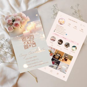 May include: A business card and a phone screen displaying a candle company's Instagram profile. The business card features a floral arrangement, candles, and the company name "Cozy Candle Co." The Instagram profile showcases candle images.