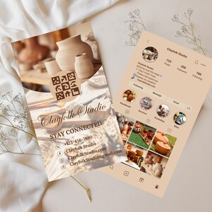 May include: Two cards with the text "Clayfolk Studio" and contact information, including a phone number and email address. The cards are on a white surface with a sprig of greenery. One card has a QR code.