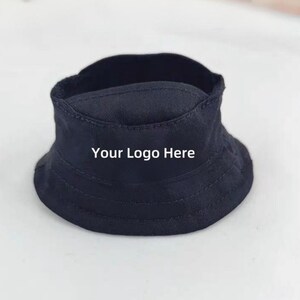 K&ouml;nnte beinhalten: Ein marineblauer Fischerhut mit dem Text "Your Logo Here" in Wei&szlig;. Der Hut hat eine runde Krone und eine nach unten geneigte Krempe. Der Hut ist aus einem robusten Stoff gefertigt.