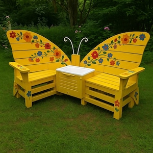 Könnte beinhalten: Eine gelbe Gartenbank in Schmetterlingsform mit eingebauter Kühlbox. Die Bank hat bemalte Blumenmuster in Rot, Orange und Blau. Die Flügel dienen als Rückenlehnen, und die Kühlbox befindet sich zwischen den beiden Sitzen. Die Bank ist aus Holz und für den Außenbereich geeignet.