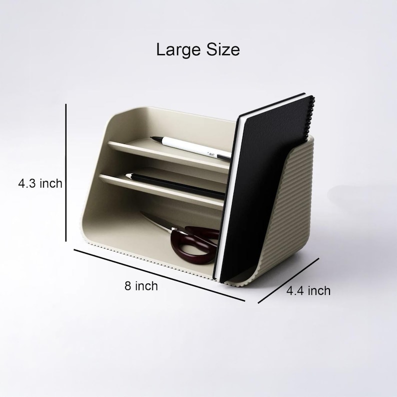 May include: A beige desk organizer with a ribbed side panel, featuring two horizontal shelves and a vertical slot. It holds a black notebook, two pens, and scissors. Text indicates Large Size, 4.3 inches high, 8 inches wide, and 4.4 inches deep.