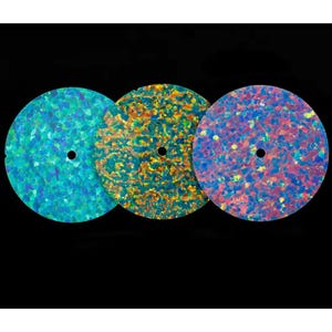 Peut inclure: Trois disques plats circulaires présentant un motif mosaïque vibrant de flocons iridescents. Le disque de gauche affiche des nuances de bleu et de sarcelle, le disque central montre des tons dorés et orange, et le disque de droite présente des teintes roses et violettes.