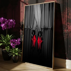 Puede incluir: Impresión artística enmarcada que presenta tacones altos negros con suelas rojas, sobre un fondo negro con una superficie reflectante. La imagen incluye piernas con medias de rejilla y un telón de fondo negro.