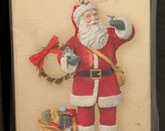 May include: Hallmark Keepsake Christmas ornament depicting Santa Claus in a red suit, holding a bird and a bag of gifts. The ornament is in a box with the text "Santa's Visit".
