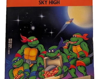Puede incluir: Portada del libro "Teenage Mutant Ninja Turtles: Sky High". La imagen muestra a las cuatro tortugas, cada una con una máscara de diferente color, comiendo pizza. El fondo es un cielo nocturno con una nave espacial. El título y el autor son visibles.