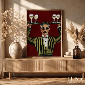Op de afbeelding: Een ingelijste kunstdruk met een gestileerde illustratie van een persoon met een snor en zonnebril in een geel en zwart gestreept jasje. De figuur houdt twee dienbladen met wijnglazen vast tegen een effen dieprode achtergrond.