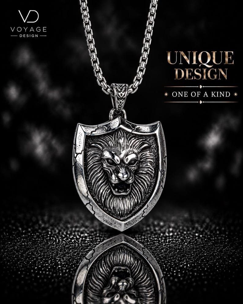 May include: A silver-toned metal pendant necklace featuring a detailed lion head relief centered on a shield-shaped plaque with cracked edge detailing. The pendant hangs from a box chain. Text on the image reads VOYAGE DESIGN, UNIQUE DESIGN, ONE OF A KIND.