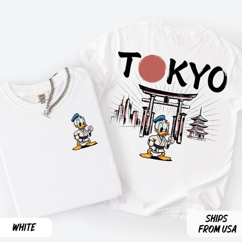 K&ouml;nnte beinhalten: Zwei wei&szlig;e T-Shirts. Eines zeigt eine Donald Duck-Grafik und das Wort "WHITE". Das andere hat "TOKYO" in schwarzer Schrift mit einem roten Kreis, einem japanischen Tor und einer Pagode. Beide Shirts haben eine Donald Duck-Grafik.