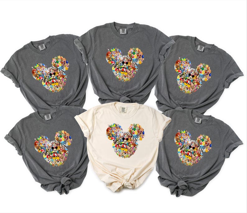 May include: Six t-shirts in shades of grey and cream. Each shirt displays a Mickey Mouse head design, composed of various colourful cartoon characters. The shirts are made of a soft material with short sleeves.