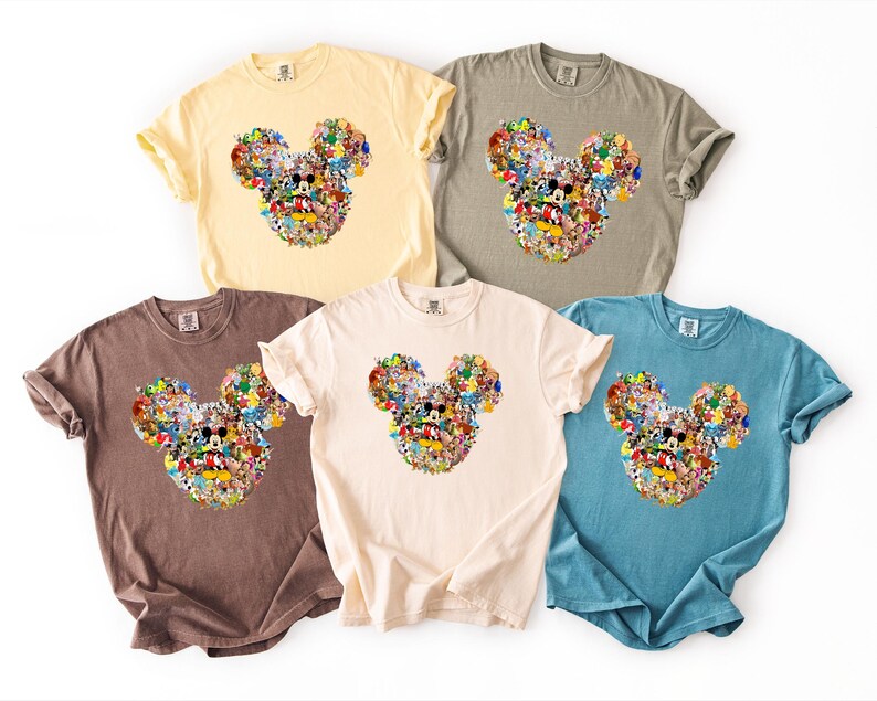 May include: Five short-sleeved t-shirts in various colours: yellow, grey, brown, cream, and blue. Each shirt features a Mickey Mouse head design made up of various cartoon characters. The shirts are made of a soft material.