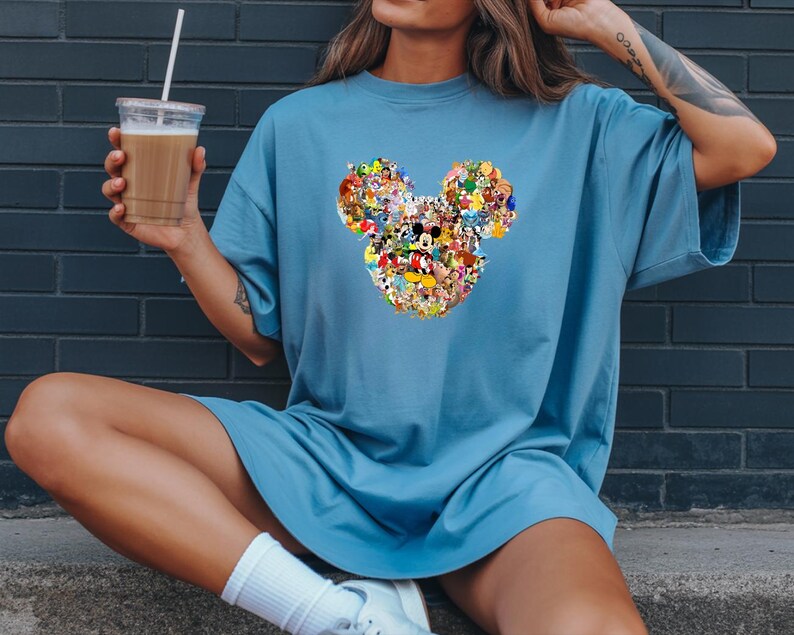 May include: A white ceramic mug with a black handle and the text "But First, Coffee" in a bold, black font. The mug is set against a neutral background, highlighting its simple design.