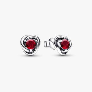 May include: A pair of silver stud earrings. Each earring features a vibrant red gemstone set in a swirling, knot-like design. The earrings are displayed against a plain white background.