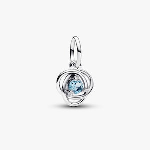 Può includere: Un charm color argento con un design a nodo. Il charm presenta una gemma blu chiaro al centro, circondata da tre piccole gemme trasparenti. Il charm ha un anello nella parte superiore per il fissaggio a un braccialetto o una collana.