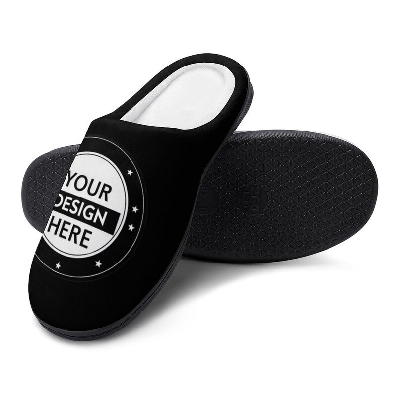 Pode incluir: Chinelo preto com interior branco e sola preta. O chinelo apresenta um design circular com o texto "YOUR DESIGN HERE" em branco. A sola tem um padr&atilde;o texturizado.