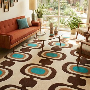 Puede incluir: Un sal&oacute;n de estilo retro con un sof&aacute; color &oacute;xido, sillas de madera y una alfombra estampada. La alfombra tiene un fondo crema con formas ovaladas marrones, turquesas y beige. Una mesa de centro y decoraci&oacute;n de pared completan el espacio.