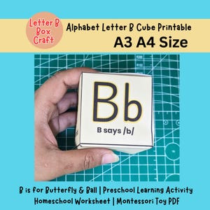 Peut inclure: Un cube imprimable avec la lettre B de l'alphabet. Le cube est tenu par une main et présente la lettre "Bb" en gras, en noir, avec un contour jaune. Le texte "B says /b/" est en dessous. L'image comprend également le texte "A3 A4 Size".