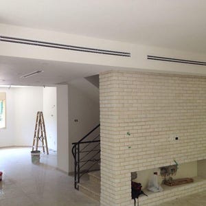 Può includere: Vista interna di una casa in costruzione. Presenta un camino in mattoni bianchi, una scala con ringhiera nera e una scala. Le pareti sono bianche e i pavimenti sono piastrellati. Le prese d'aria sono installate nel soffitto.