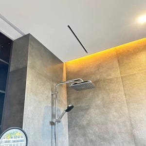 May include: A contemporary shower installation featuring a square rain shower head and a handheld shower. Chrome fixtures are set against grey tiled walls. The ceiling includes a recessed light and a warm light strip.